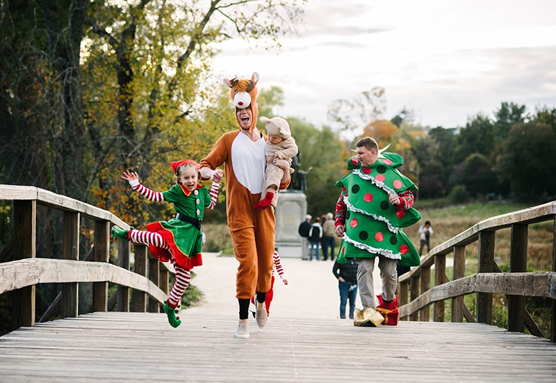 family runs across Old North Bridge in Concord, MA wearing Christmas costumes