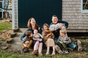 Family photography, a family of six sit outside their home laughing with their dog