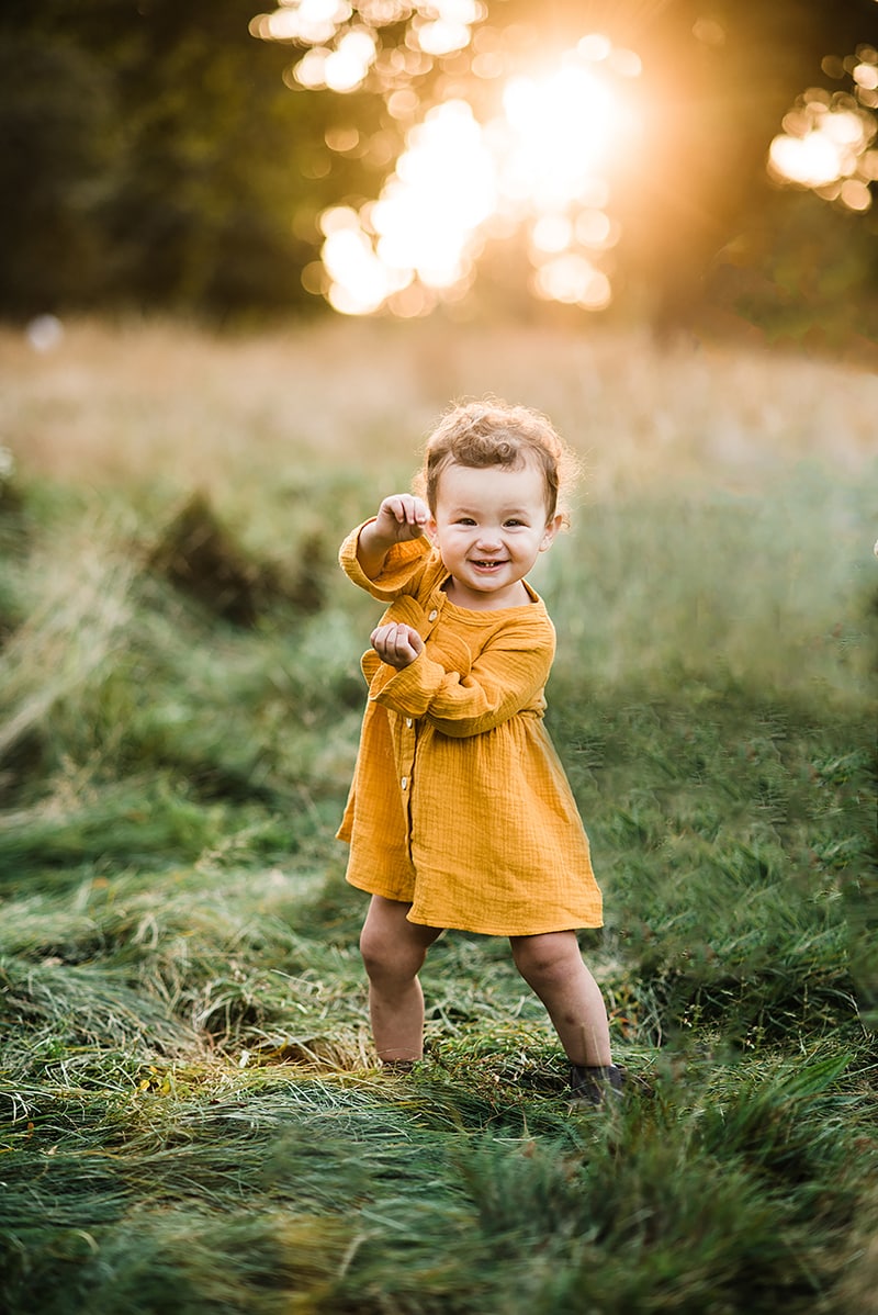 toddler girl in yellow dress does the baby shark dance in a field