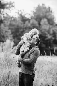 black and white image of toddler daughter resting on dad's shoulder with her head on his.