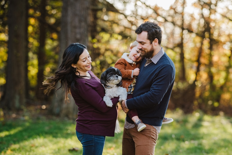 Family Photographer, dad holds child outdoors, mom holds their puppy