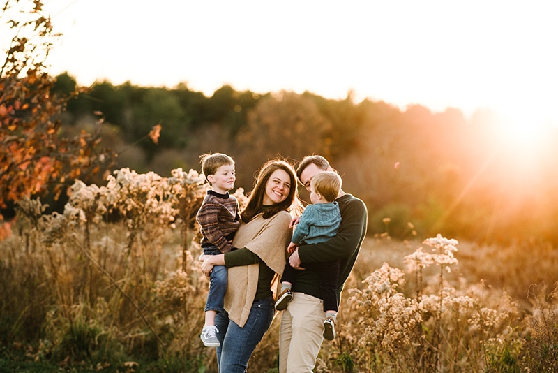 family of four stands in golden light in a field in Burlington, mA