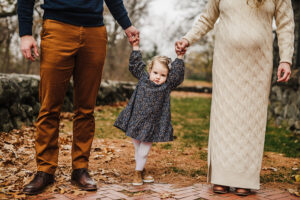 soon to be big sister holds mom and dad's hands during family maternity session