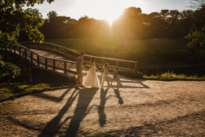 beautiful image of family walking in a row in front of Old North Bridge in Concord, MA during golden hour