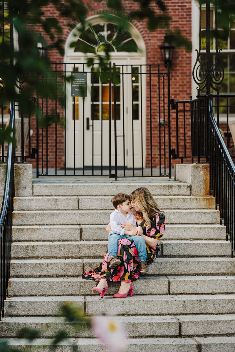 mother and son sit nose to nose on a staircase in Harvard Square's Radcliffe Courtyard